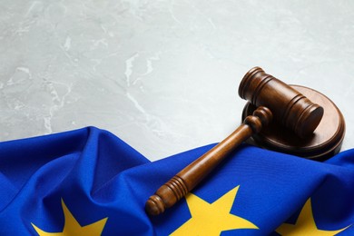 Photo of Judge's gavel and flag of European Union on light grey marble table. Space for text