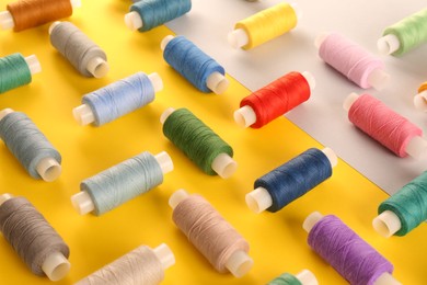 Photo of Set of different sewing threads on color background