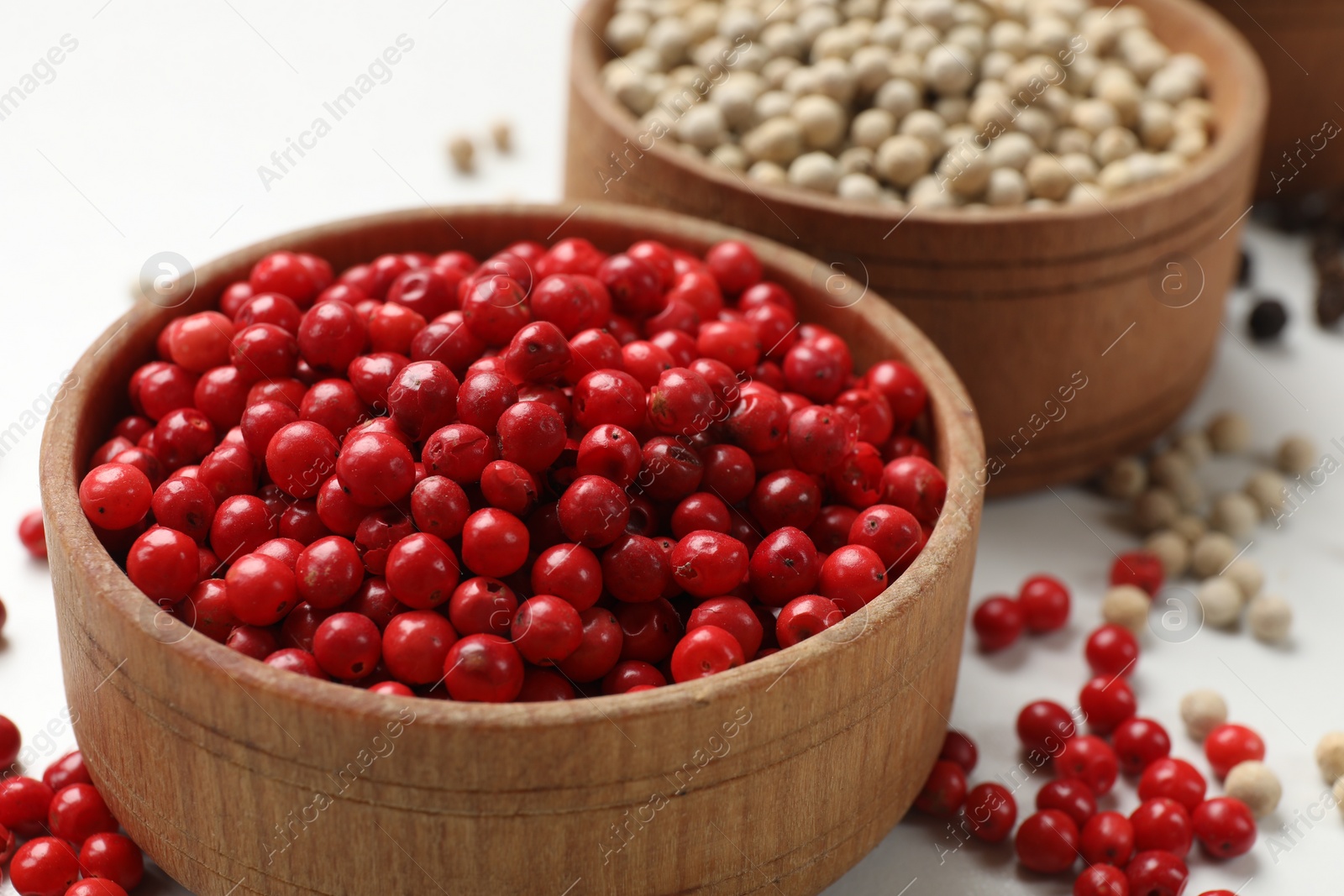 Photo of Aromatic spice. Different peppers in bowls on white table, closeup