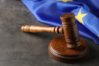 Photo of Wooden judge's gavel and flag of European Union on grey table. Space for text