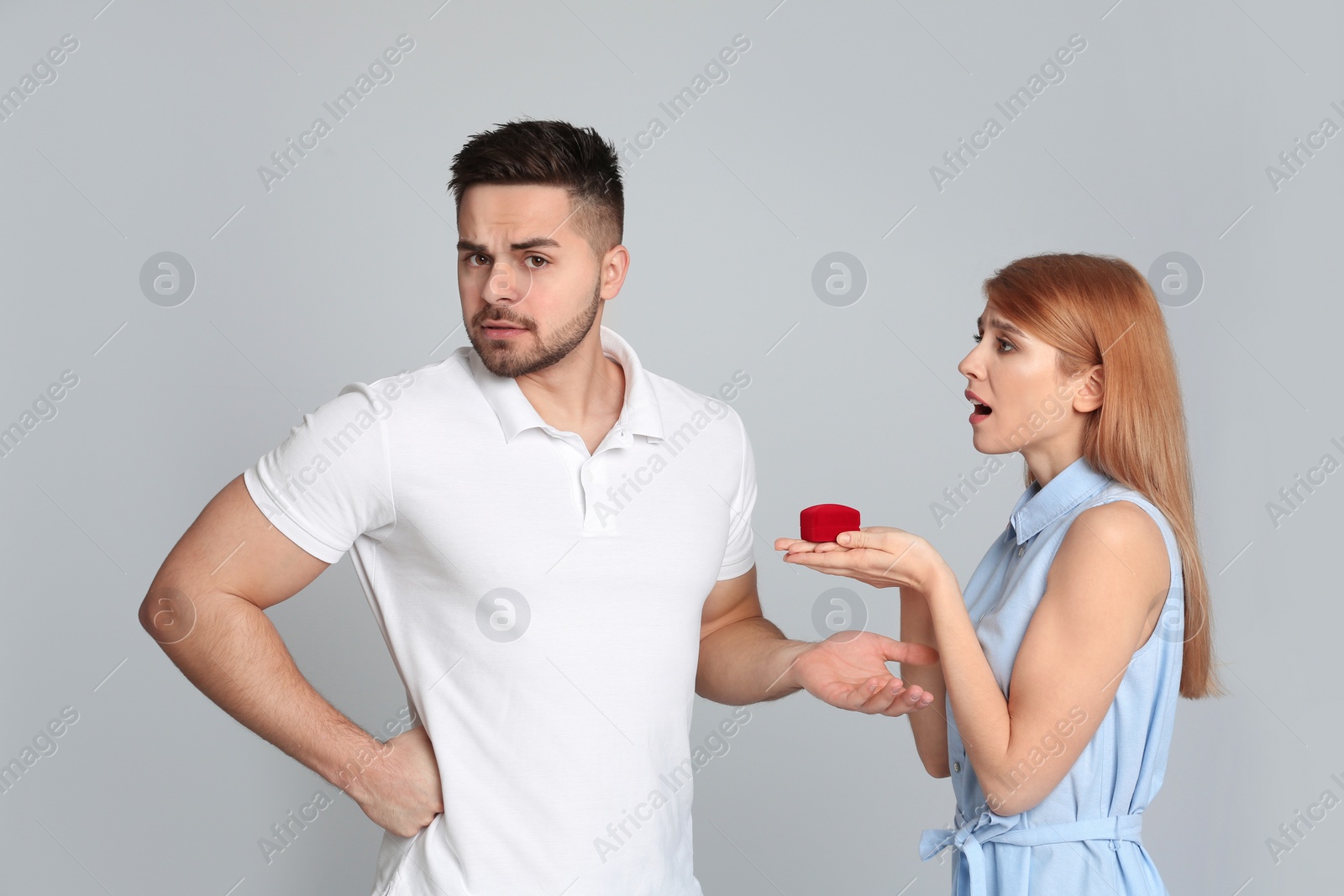 Photo of Young woman with engagement ring making marriage proposal to her boyfriend on light grey background