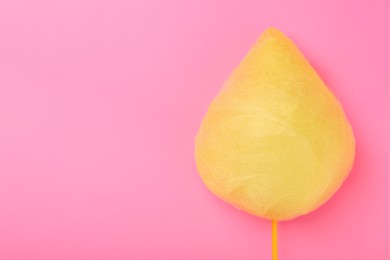 One sweet yellow cotton candy on pink background, top view. Space for text