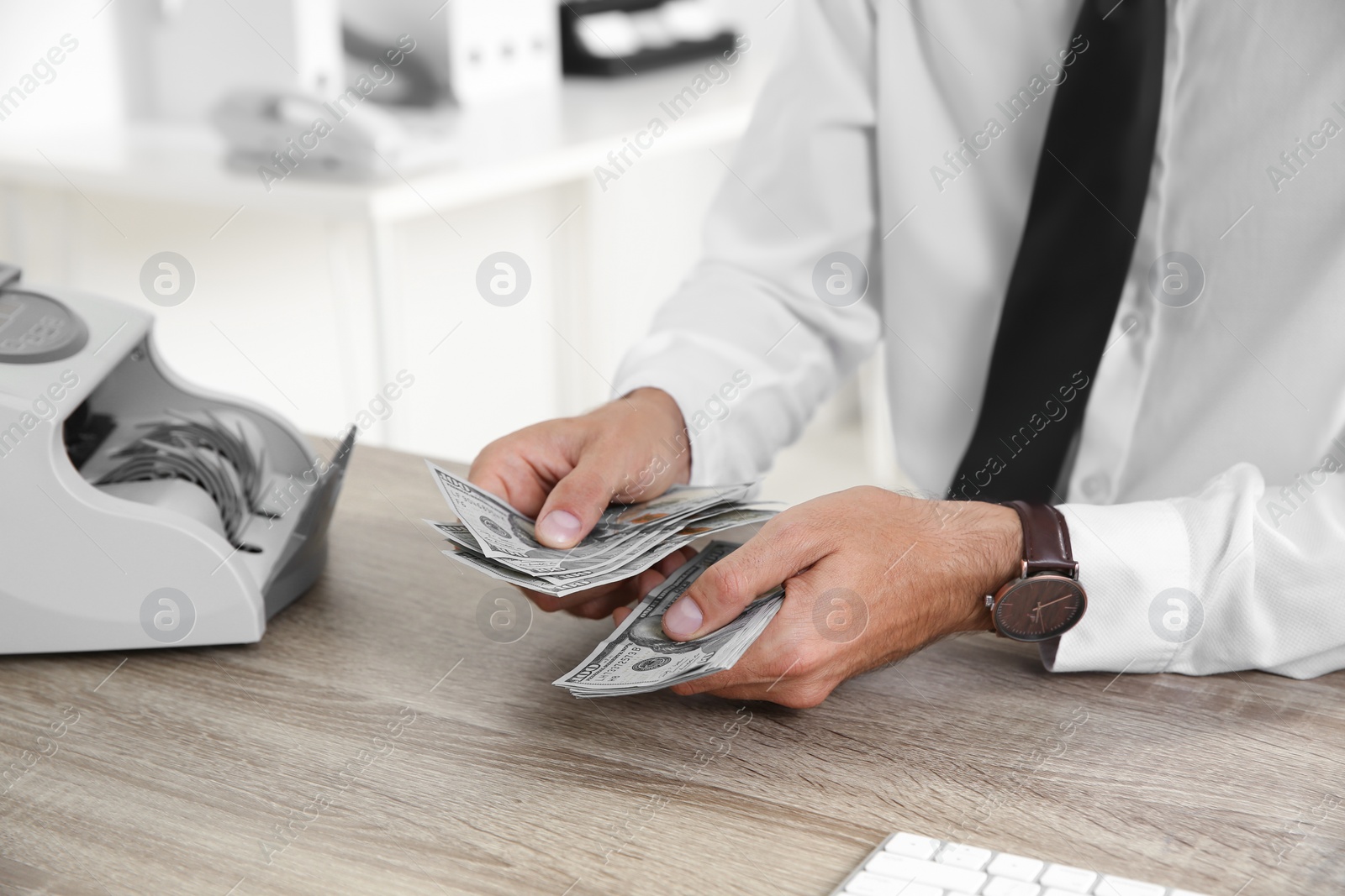 Photo of Male teller counting money at cash department, closeup