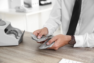 Male teller counting money at cash department, closeup