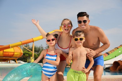 Happy family with inflatable ring near pool in water park