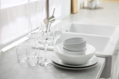 Photo of Different clean dishware and glasses on countertop near sink in kitchen