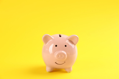 Cute pink piggy bank on yellow background