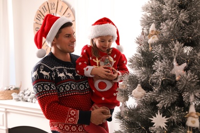 Photo of Father and daughter with snow globe near Christmas tree at home