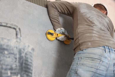 Photo of Worker installing wall tile with vacuum holder indoors, closeup