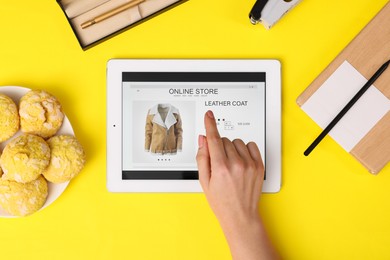 Photo of Woman with tablet shopping online on yellow background, top view