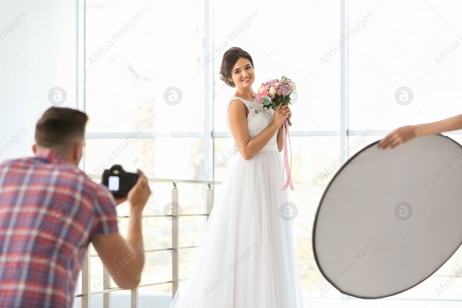 Photo of Professional photographer taking photo of beautiful bride in studio