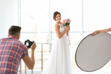 Photo of Professional photographer taking photo of beautiful bride in studio