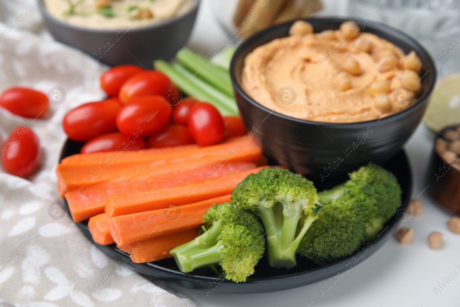 Photo of Plate with delicious hummus and fresh vegetables on white table, closeup