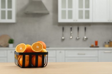 Photo of Fresh ripe oranges on wooden table in kitchen, space for text