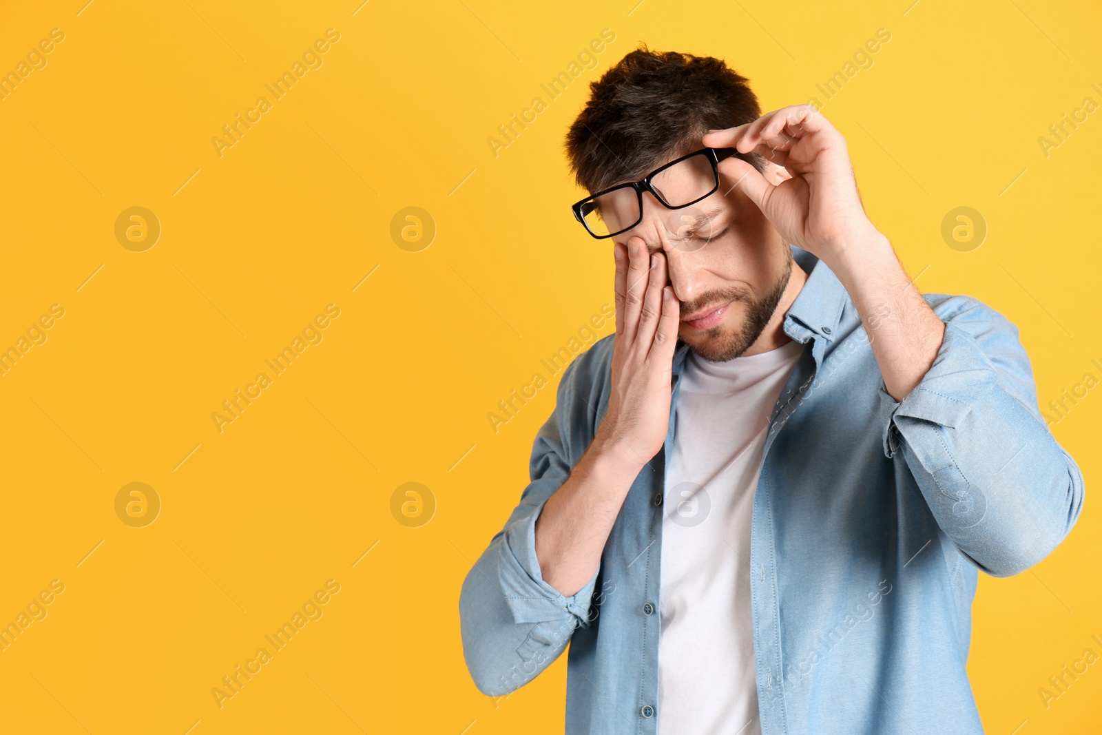 Photo of Man suffering from terrible migraine on yellow background. Space for text