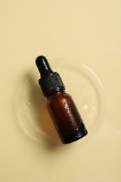 Bottle of cosmetic serum on beige background, top view