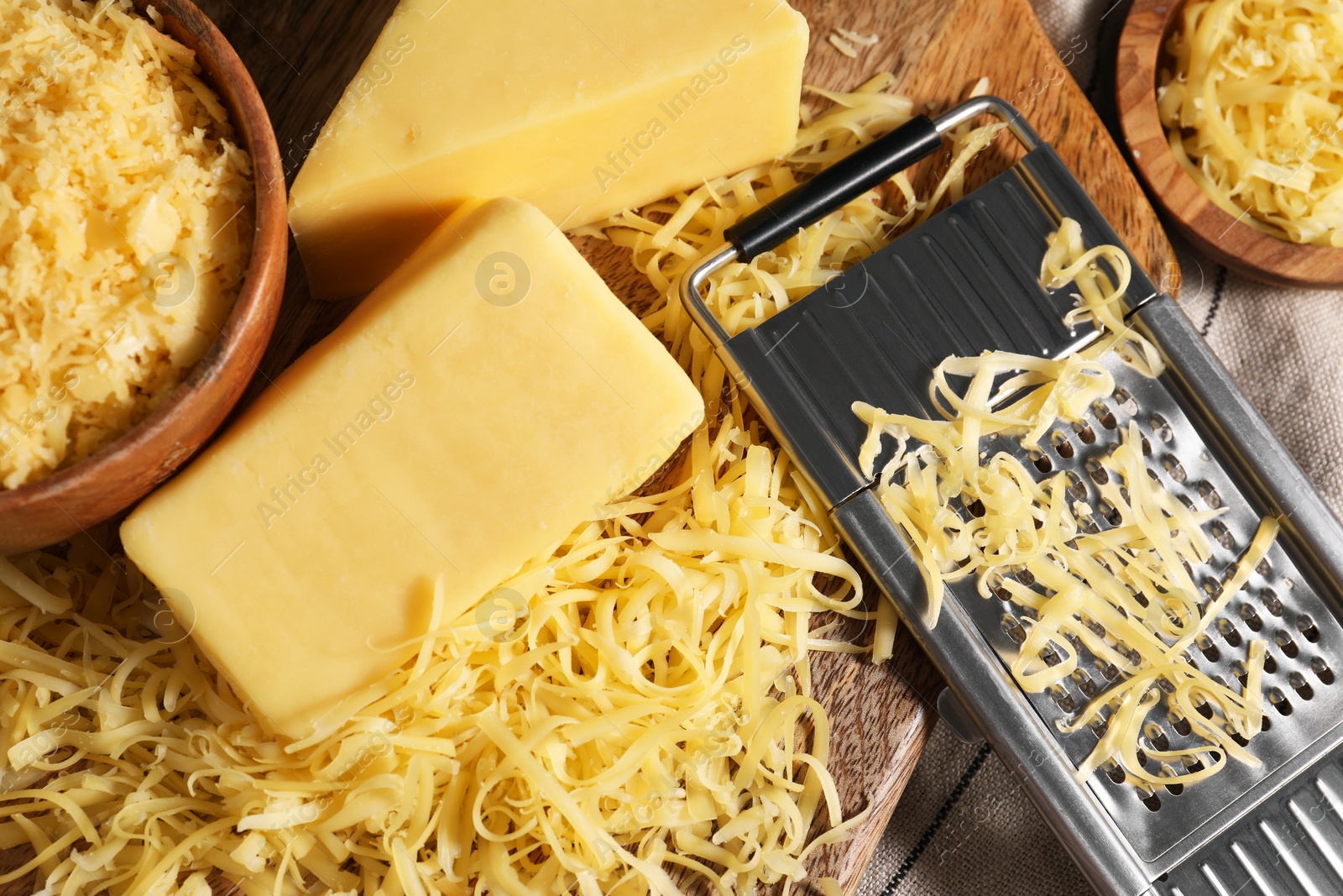 Photo of Grated, whole pieces of cheese and grater on table, top view