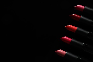 Many bright lipsticks on black background, flat lay, space for text