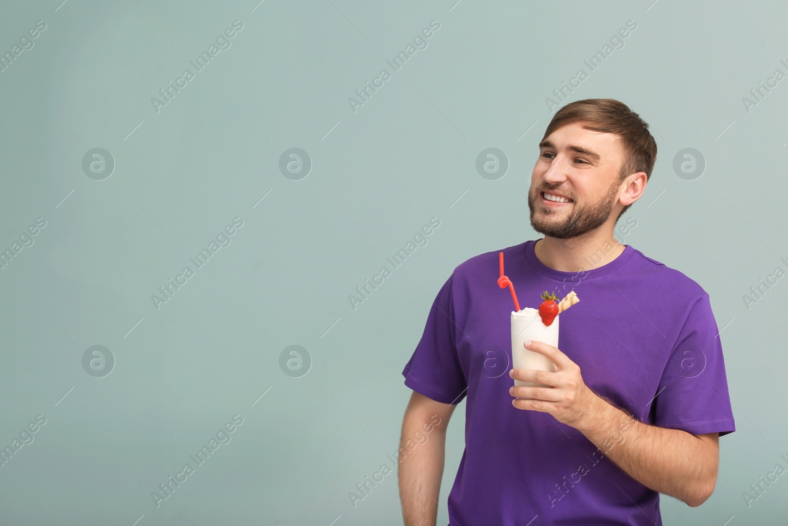 Photo of Young man with glass of delicious milk shake on color background