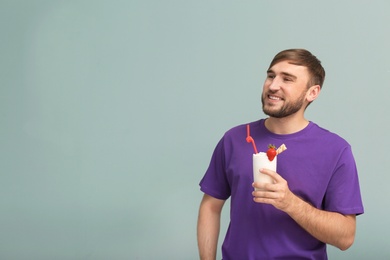 Photo of Young man with glass of delicious milk shake on color background