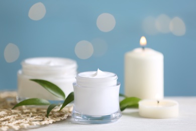 Photo of Beautiful spa composition with cosmetic products and candles on white table, closeup