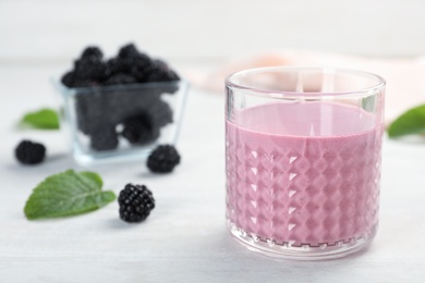 Photo of Glass with tasty blackberry yogurt smoothie on table