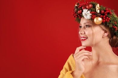 Photo of Beautiful young woman wearing Christmas wreath on red background. Space for text