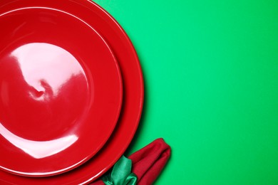 Set of ceramic dishware on green background, flat lay. Space for text