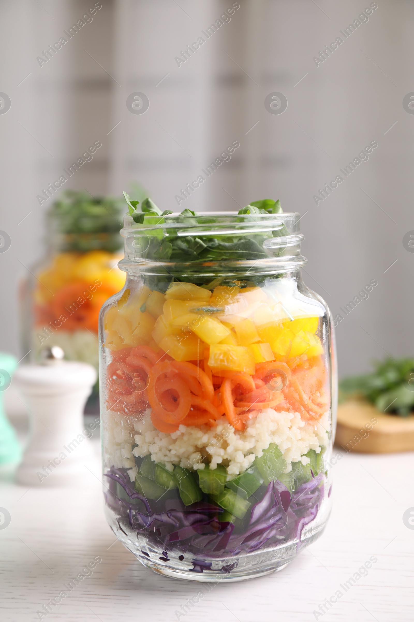 Photo of Healthy salad in glass jar on white wooden table