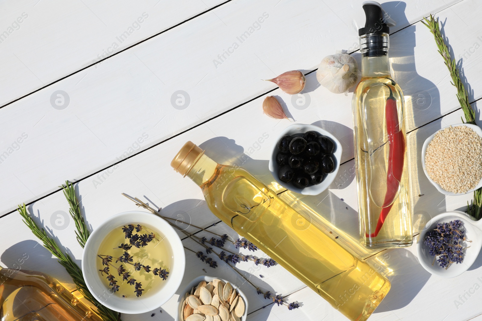 Photo of Different cooking oils and ingredients on white wooden table, flat lay. Space for text