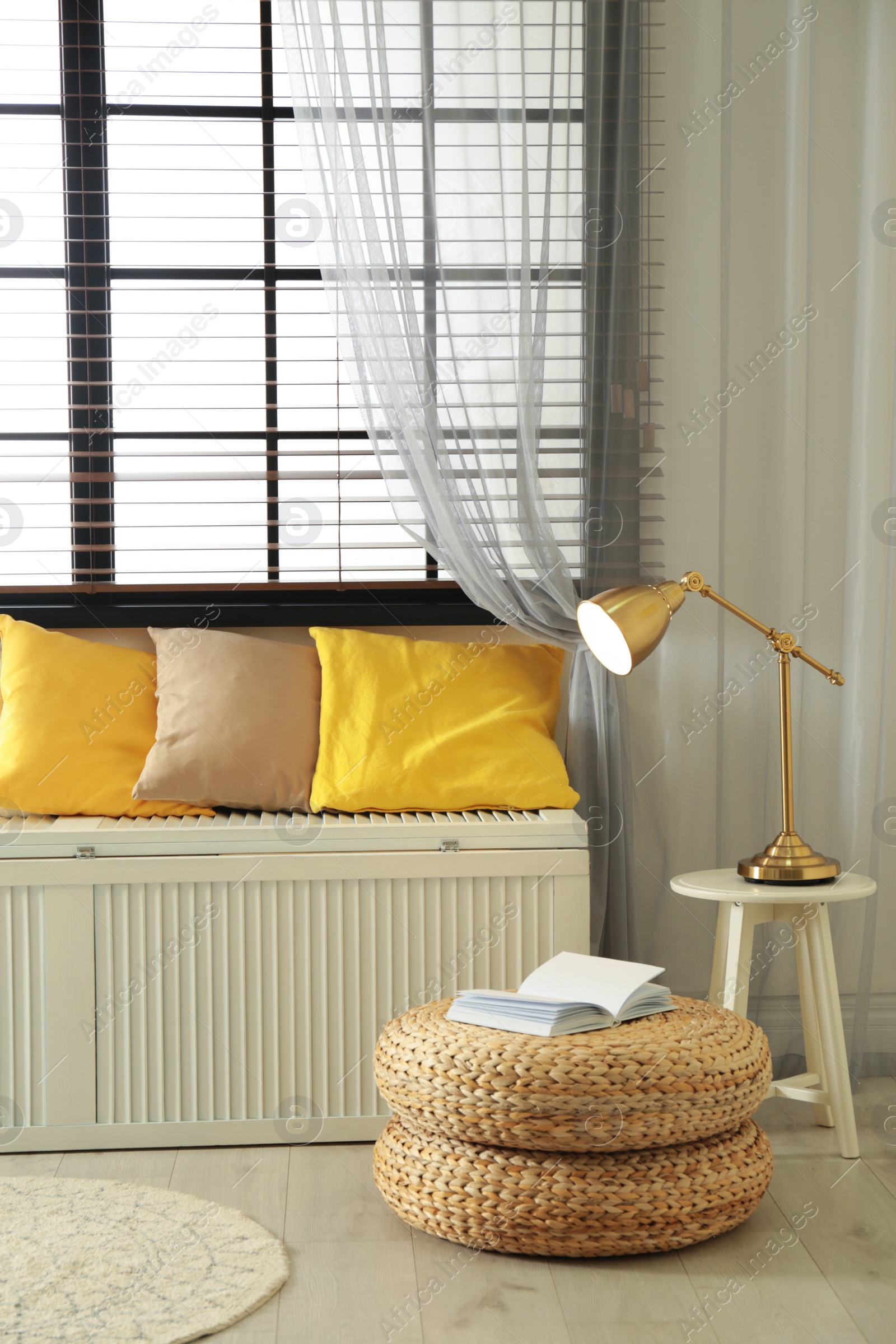 Photo of Wooden chest with pillows near window in room. Interior design