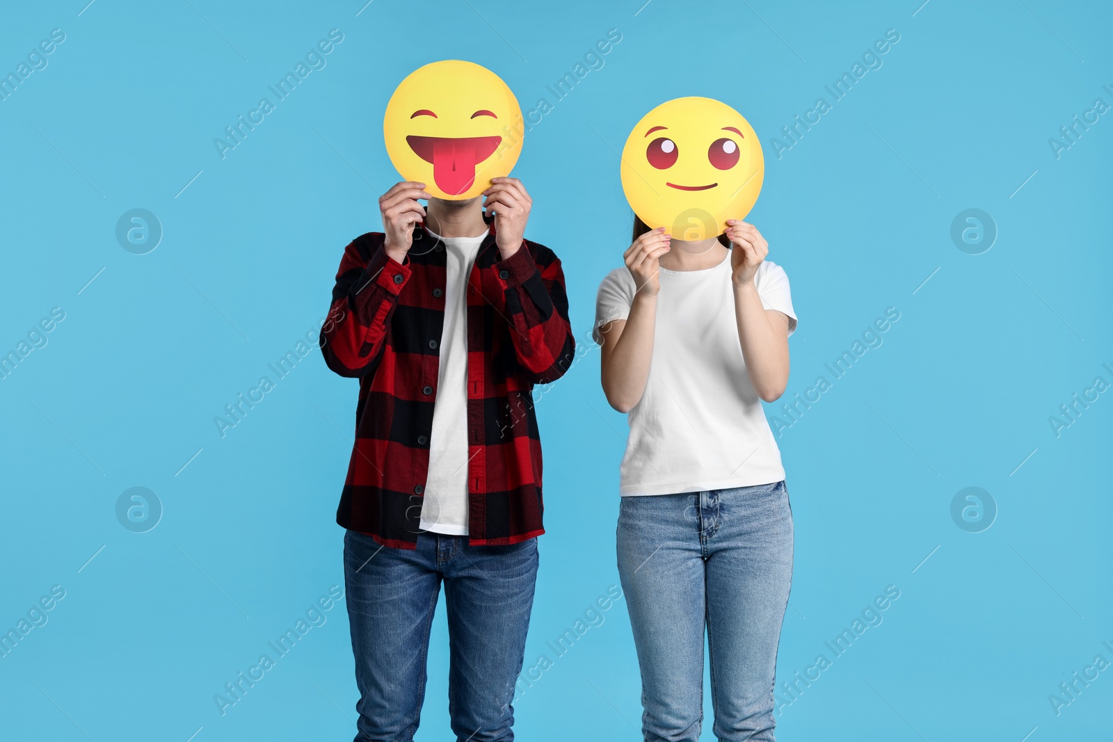 Photo of People covering faces with emoticons on light blue background