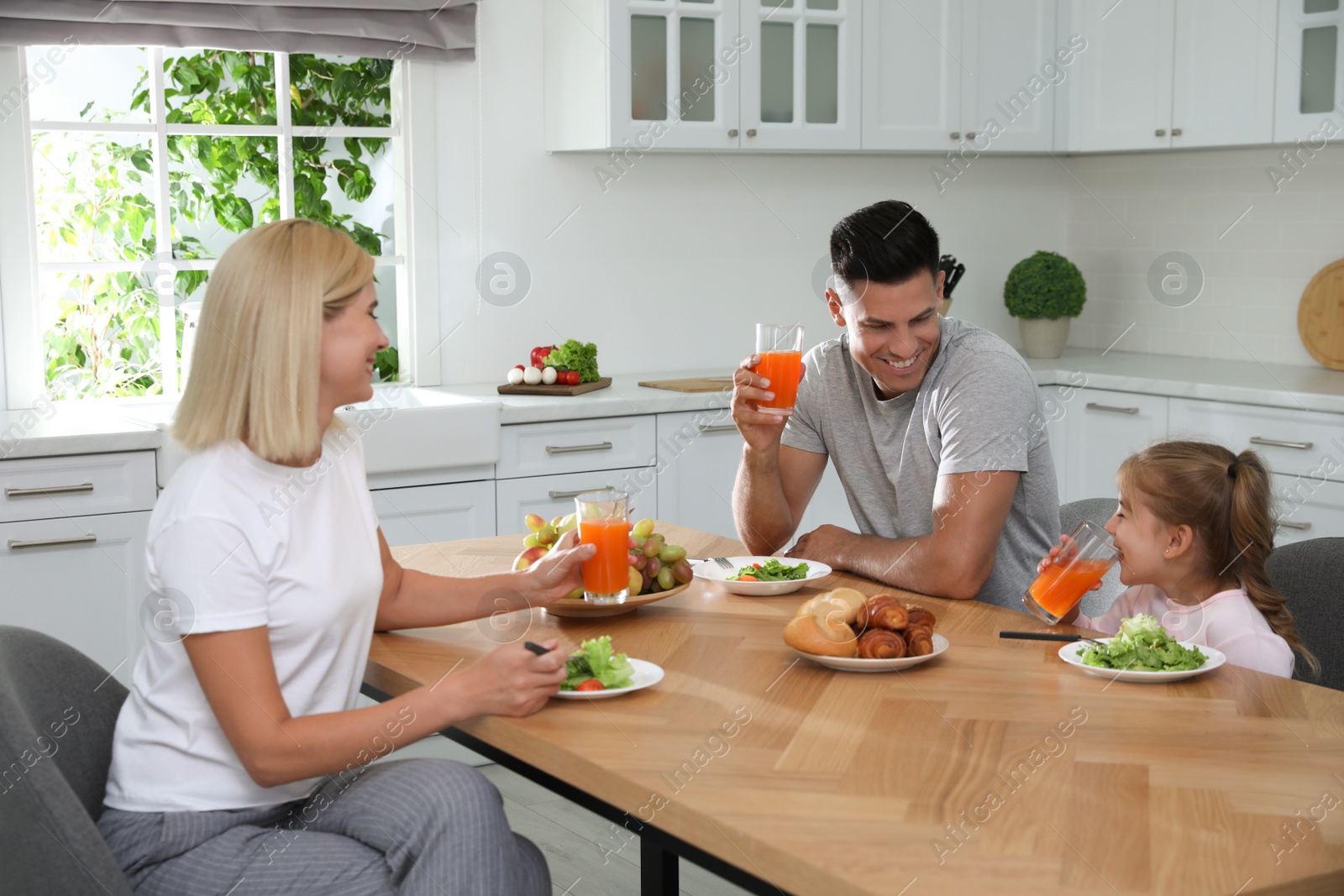 Photo of Happy family having breakfast together at table in modern kitchen