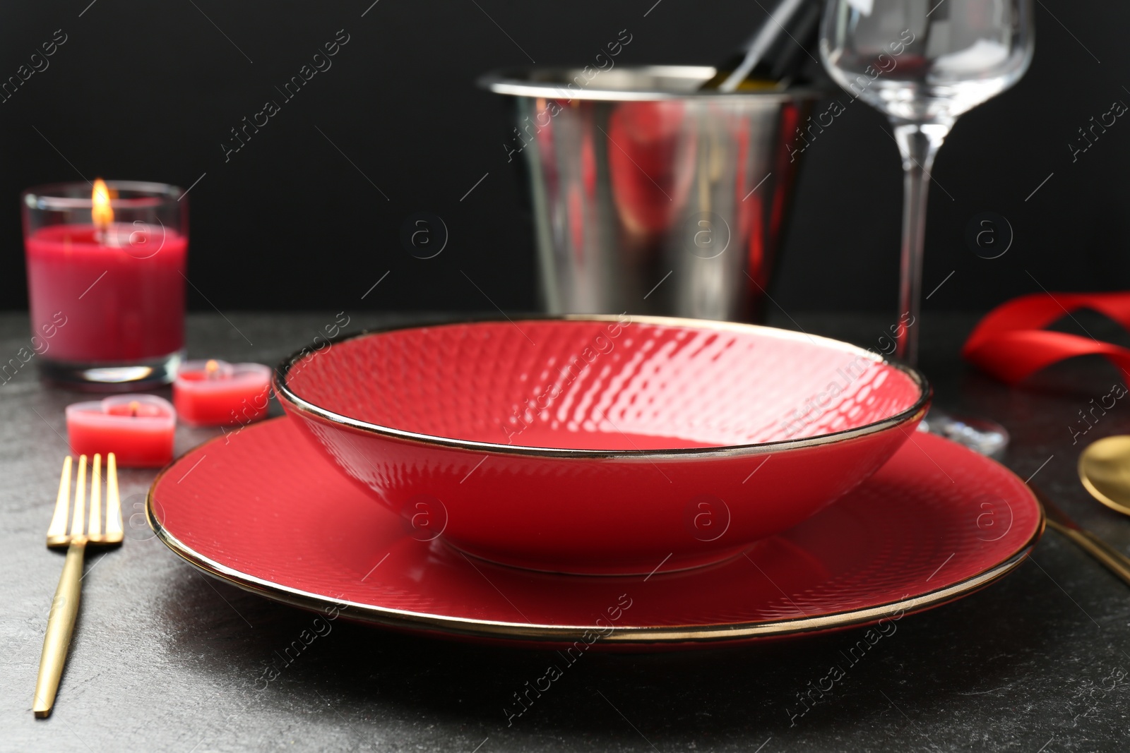 Photo of Place setting with heart shaped candles on dark gray table, closeup. Romantic dinner