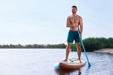 Photo of Man paddle boarding on SUP board in sea, space for text