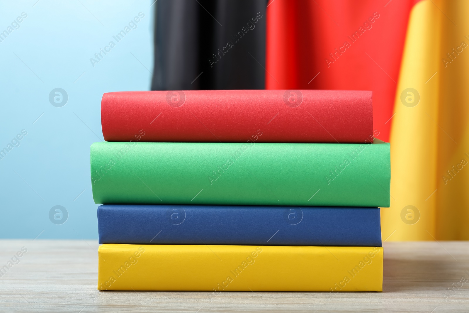 Photo of Learning foreign language. Different books on wooden table near flag of Germany