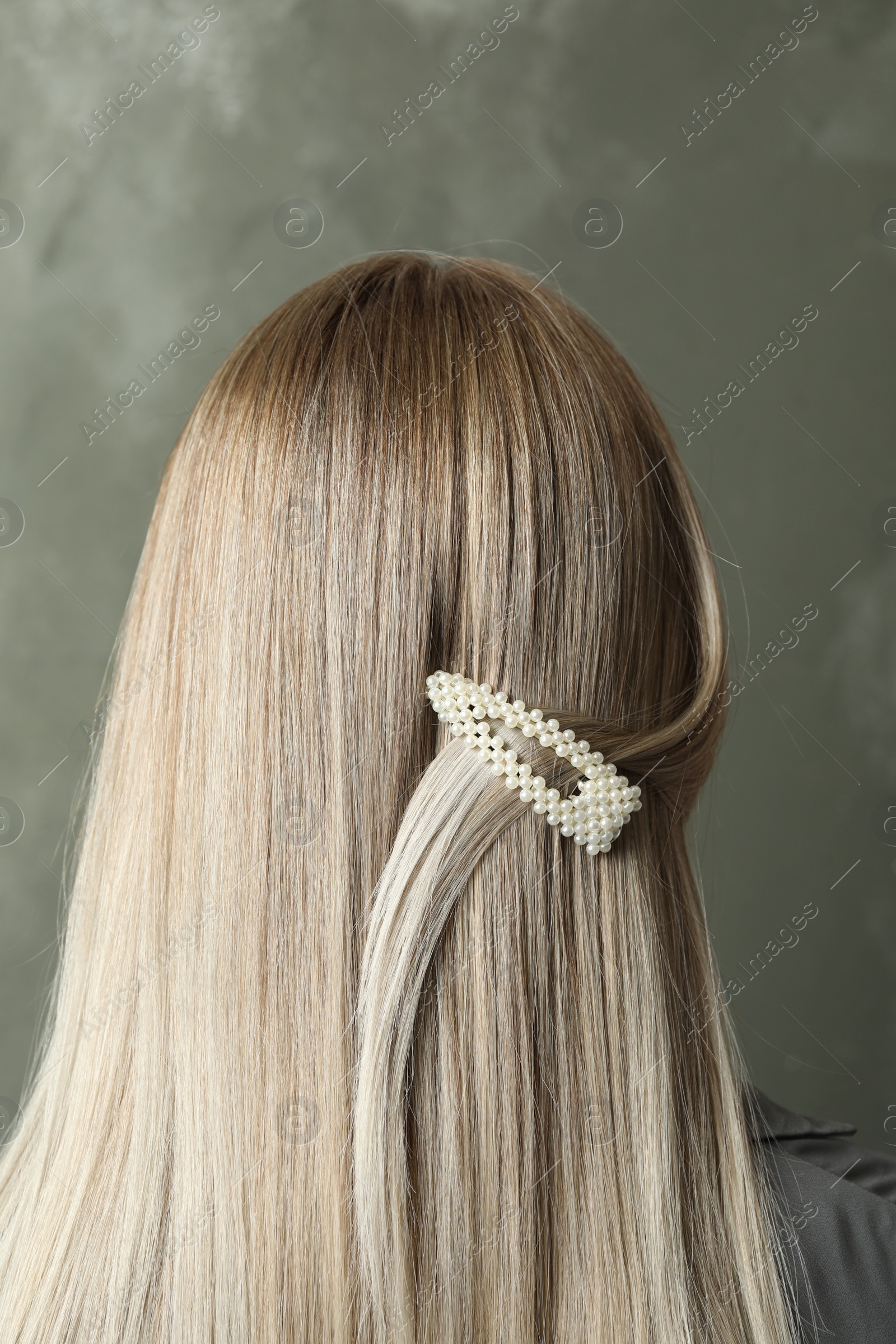 Photo of Young woman with beautiful hair clip on grey background, back view