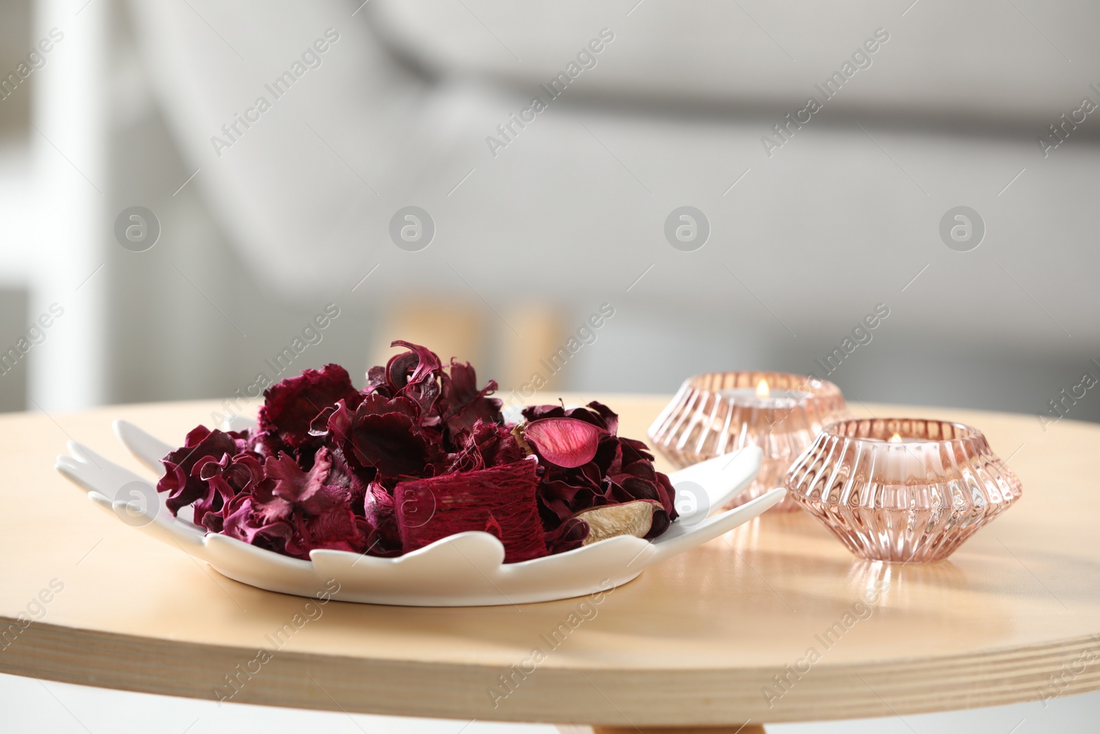Photo of Aromatic potpourri of dried flowers and candles on coffee table indoors