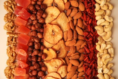 Mix of delicious dried nuts and fruits on beige background, flat lay