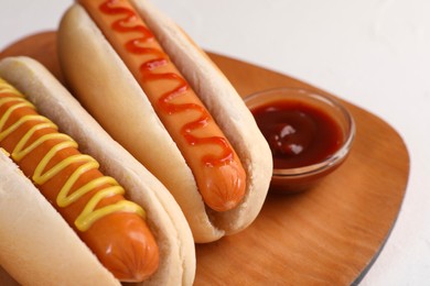 Photo of Tasty hot dogs with ketchup and mustard on white table, closeup