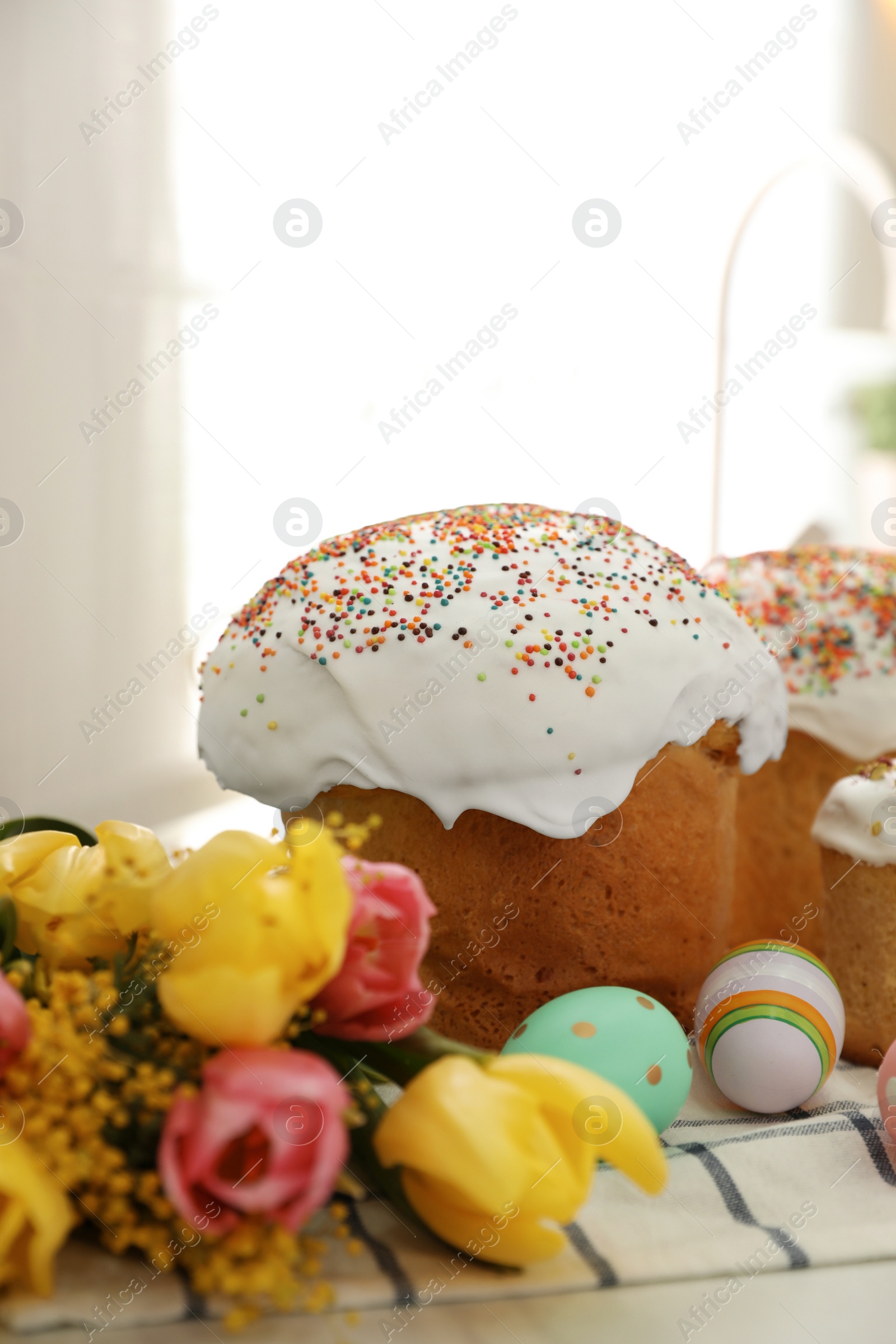 Photo of Traditional Easter cakes, flowers and dyed eggs on table, closeup