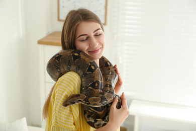 Young woman with boa constrictor at home. Exotic pet