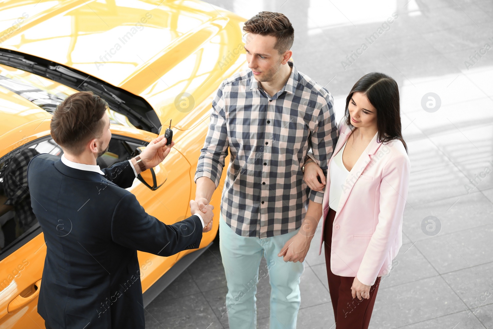 Photo of Young couple buying new car in salon