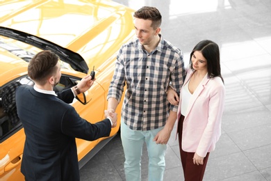 Young couple buying new car in salon