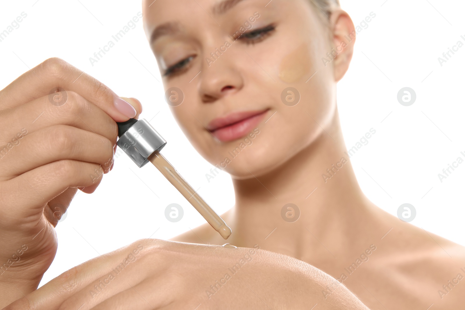 Photo of Young woman testing liquid foundation on her hand against white background