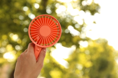 Woman holding portable fan outdoors on sunny summer day, closeup. Space for text