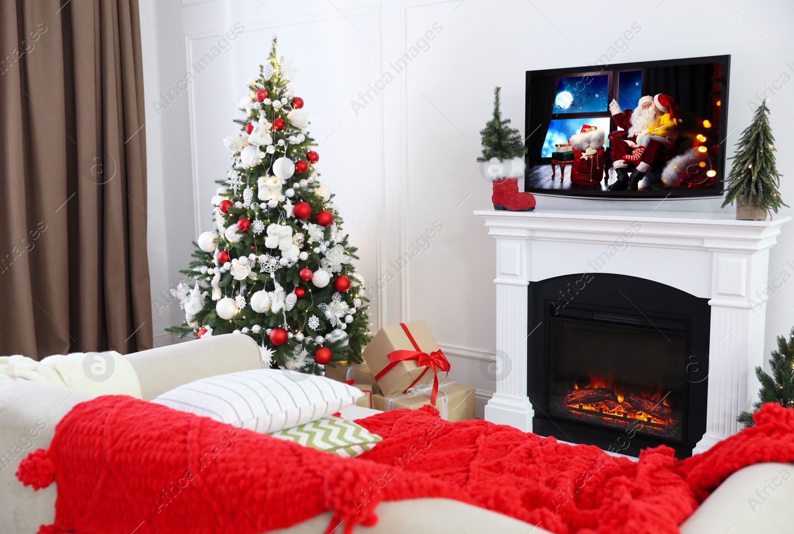 Image of Modern TV set on fireplace in room decorated for Christmas
