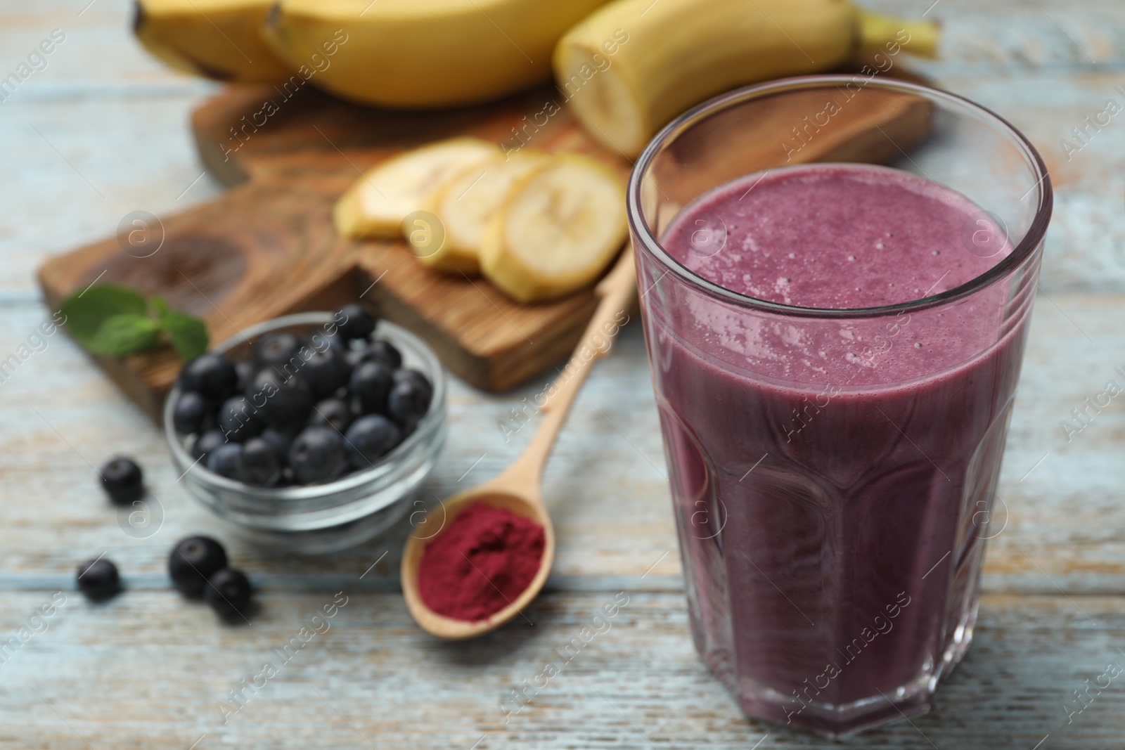 Photo of Fresh acai drink with powder and berries on wooden table