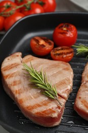 Photo of Delicious tuna steak with rosemary and tomatoes in grill pan, closeup