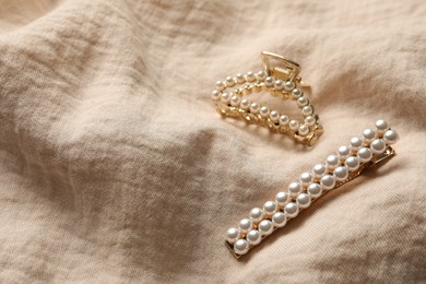 Photo of Beautiful hair clips with pearls on beige fabric. Space for text